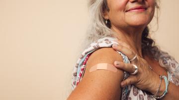 Woman showing bandage on arm after receiving flu shot