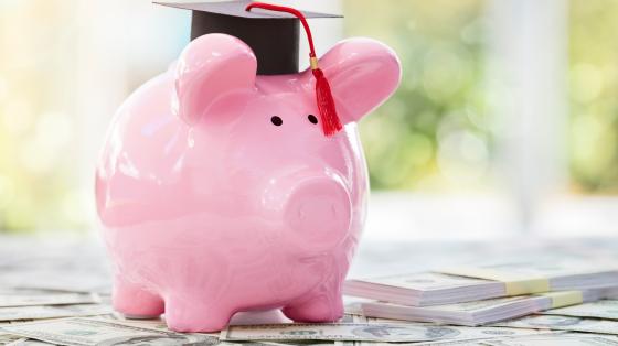 Piggy bank wear graduation cap sitting on money