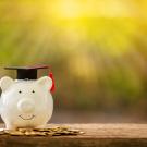Piggy bank wear graduation cap on a pile of coins